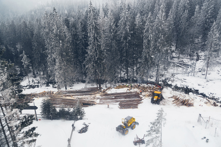 Industrial logging and harvesting with machinery in winter mountain forest. Flying drone view photography.の写真素材