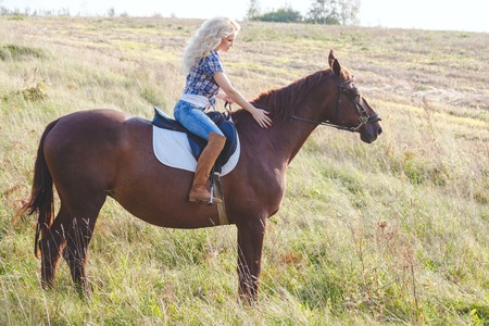 Portrait of young beautiful blond hair woman riding horse. Travel with animalの写真素材