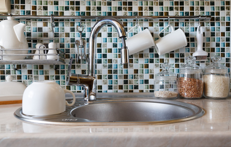 Interior of modern kitchen. Kitchen faucet, sink and various ceramic white dishesの写真素材
