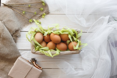 Basket with eggs and spring decor on a white wooden background.の写真素材