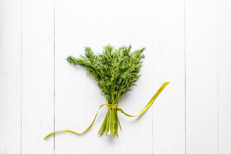 Bunch of fresh dill with ribbon on white wooden rustic backgroundの写真素材