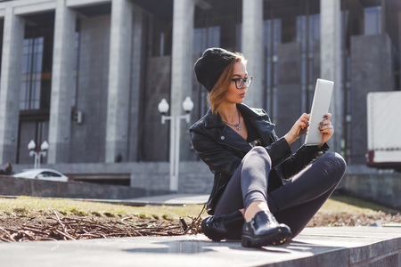 Cute girl hacker programmer working with tablet computer outdoors.の写真素材