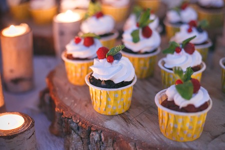 Cupcakes with berries on a wooden shelf in candle light.の写真素材