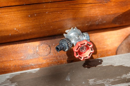 A tap for watering in the wall of a wooden houseの写真素材
