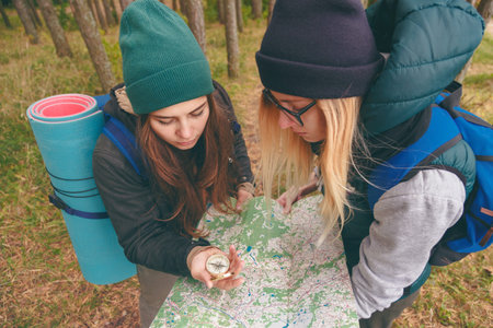 Two young tourist determine the route map and compass