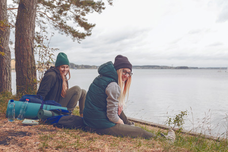 Smiling young women resting during traveling near the lakeの写真素材