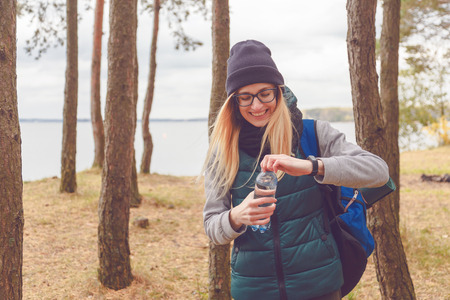 Hiker girl enjoying water. Happy woman tourist with backpack drinking water from bottle in nature.の写真素材
