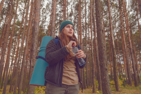 Hiker girl enjoying water. Happy woman tourist with backpack drinking water from bottle in nature.の写真素材
