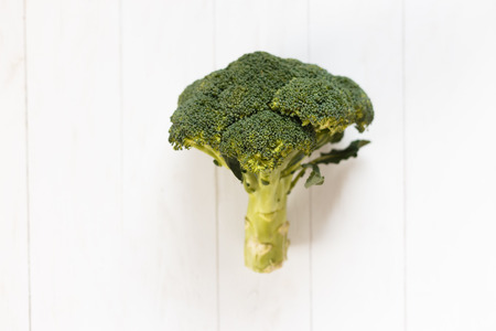 Raw food concept. Woman's hands holding bunch of broccoli over light gray background. Close up. Copy-spaceの写真素材