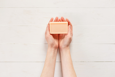 Top view of woman hands with solid soap on white wooden backgroundの写真素材