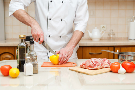 closeup on hands cutting yellow pepper on professional kitchen.の写真素材