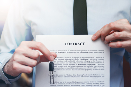 Successful businessman offering a key with contract. Rental agreement with contractの写真素材