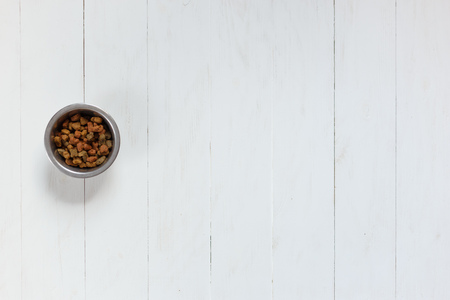 Dry pet food in bowl on white wooden background top view.の写真素材