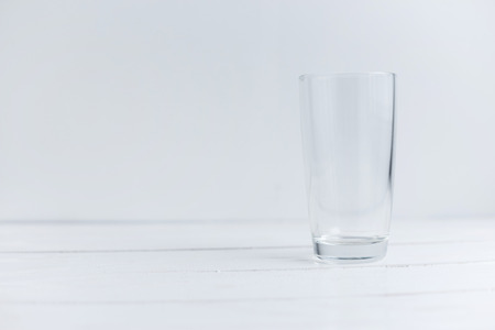 Close up view of empty glass standing on white wooden table.の写真素材