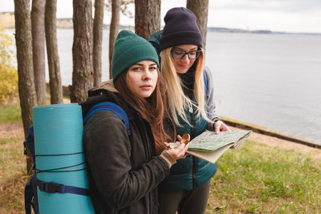 Two young tourist determine the route map and compass.
