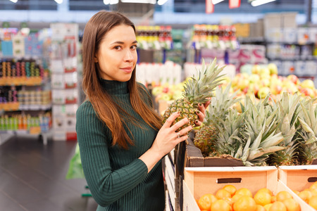 Young brunette woman buying pineappleの写真素材