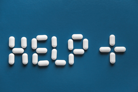 White pills with inscription HELP on blue surface backgroundの写真素材