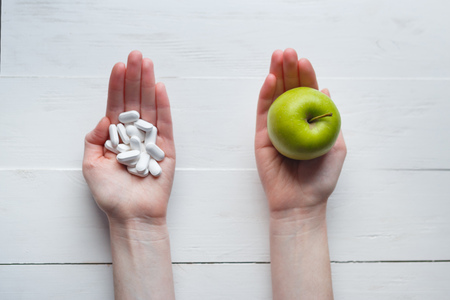 Woman holds a green apple in one hand and a handful of pills in the other. Top viewの写真素材