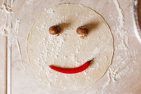 Dough basis for pizza in the shape of smile, on the tableの写真素材