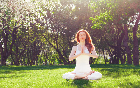 Young woman peacefully meditating in a open field.の写真素材