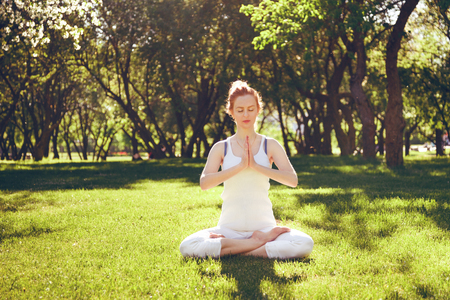 Young red hair woman peacefully meditating in parkの写真素材