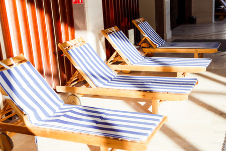 Sunlit public pool interior with chaise longuesの写真素材