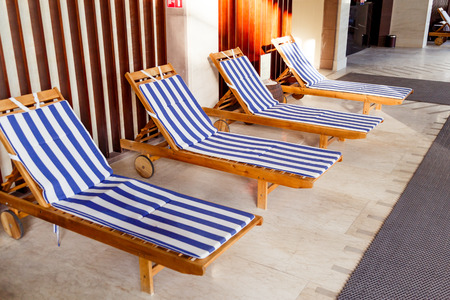Sunlit public pool interior with chaise longuesの写真素材