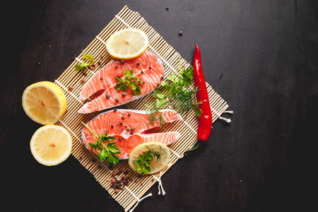 Salmon steaks with lemon and spices on black background with copy space text.の写真素材