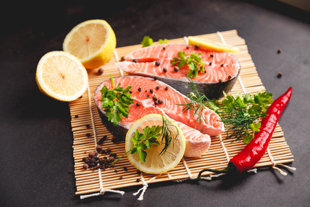 Salmon steaks with lemon and spices on black background with copy space text.の写真素材