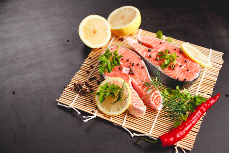 Salmon steaks with lemon and spices on black background with copy space text.の写真素材