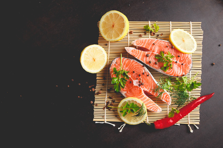 Salmon steaks with lemon and spices on black background with copy space text.の写真素材