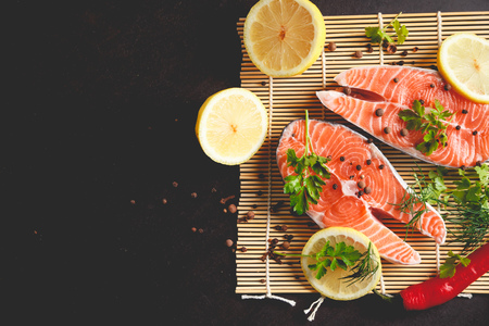 Salmon steaks with lemon and spices on black background with copy space text.の写真素材