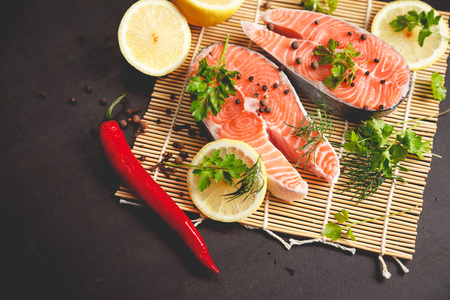 Salmon steaks with lemon and spices on black background with copy space text.の写真素材