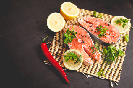 Salmon steaks with lemon and spices on black background with copy space text.の写真素材