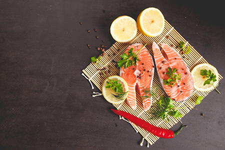 Salmon steaks with lemon and spices on black background with copy space text.の写真素材