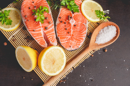 Two salmon steaks with lemon, pepper and salt. View from above.の写真素材