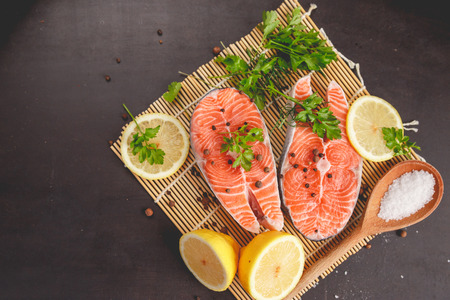 Two salmon steaks with lemon, pepper and salt. View from above.の写真素材