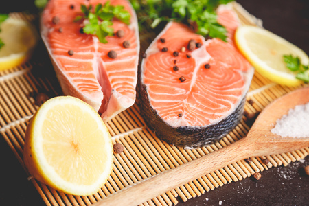 Two salmon steaks with lemon, pepper and salt. View from above.の写真素材