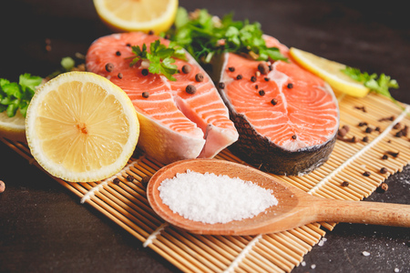 Two salmon steaks with lemon, pepper and salt. View from above.の写真素材