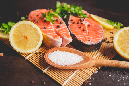 Two salmon steaks with lemon, pepper and salt. View from above.の写真素材