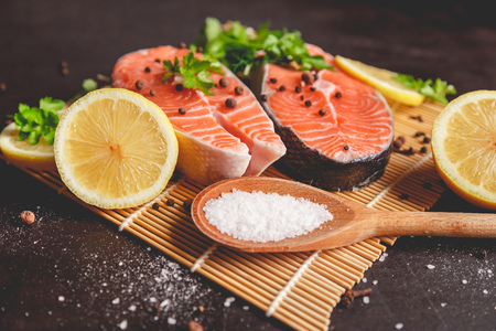 Two salmon steaks with lemon, pepper and salt. View from above.の写真素材