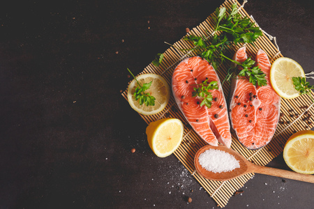 Two salmon steaks with lemon, pepper and salt. View from above.の写真素材