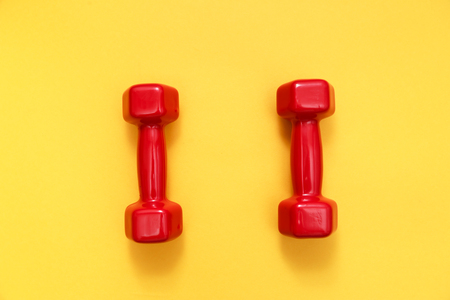 Two red womens dumbbells on yellow background.の写真素材