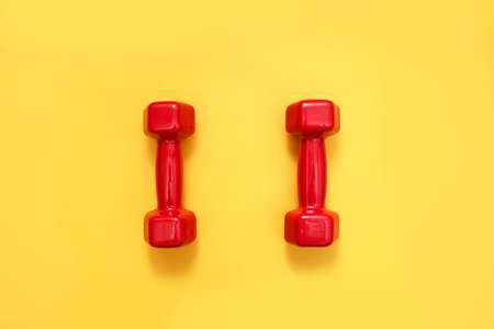 Two red womens dumbbells on yellow background.の写真素材