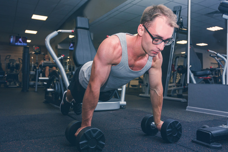 Strong man doing push-ups exercises on dumbbellsの写真素材