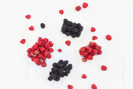 raspberries and blackberries white wooden backgroundの写真素材