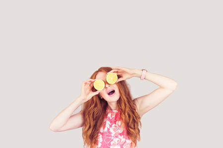 Red-hair woman keep two lemons on her eyesの写真素材