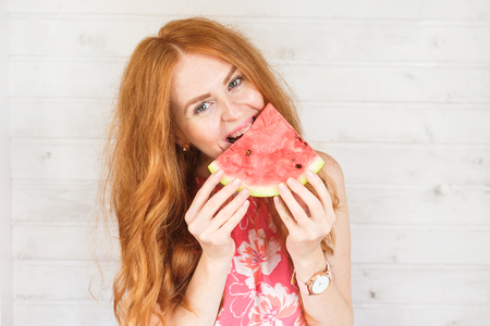 Red-hair woman is tasting a slice of watermelonの写真素材