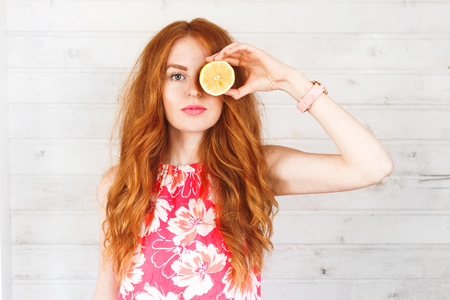 Delighted red-hair woman keep two lemons on her eyes. The portrait with a copyspaceの写真素材