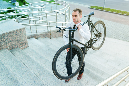 businessman carrying his bike go upstairsの写真素材